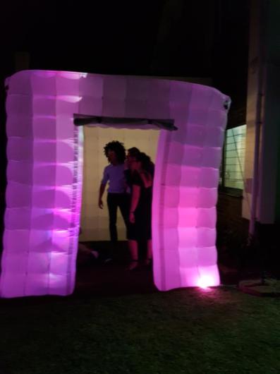 Illuminated white inflatable photo booth at an evening event